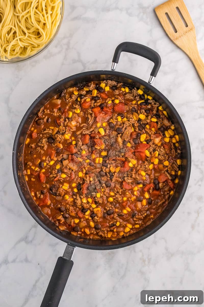 Meat with corn, black beans and tomatoes in skillet.
