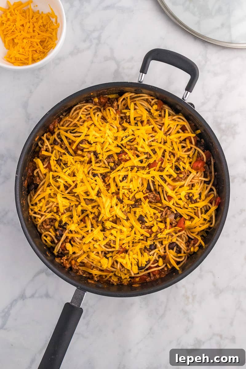 Shredded cheese is added to the top of taco spaghetti.