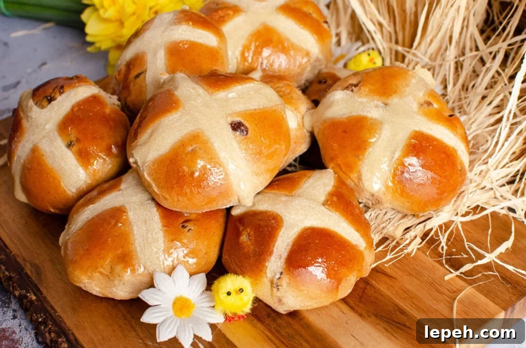 Hot Cross Buns on a wooden board with daffodils and toy chicks around them