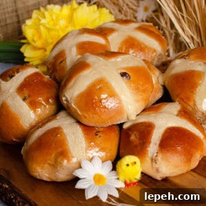Hot Cross Buns on a wooden board with daffodils and toy chicks around them