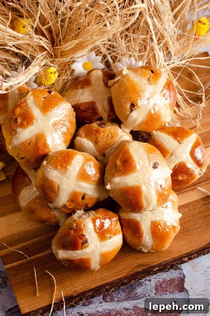 Hot Cross Buns on a wooden board with daffodils and toy chicks around them