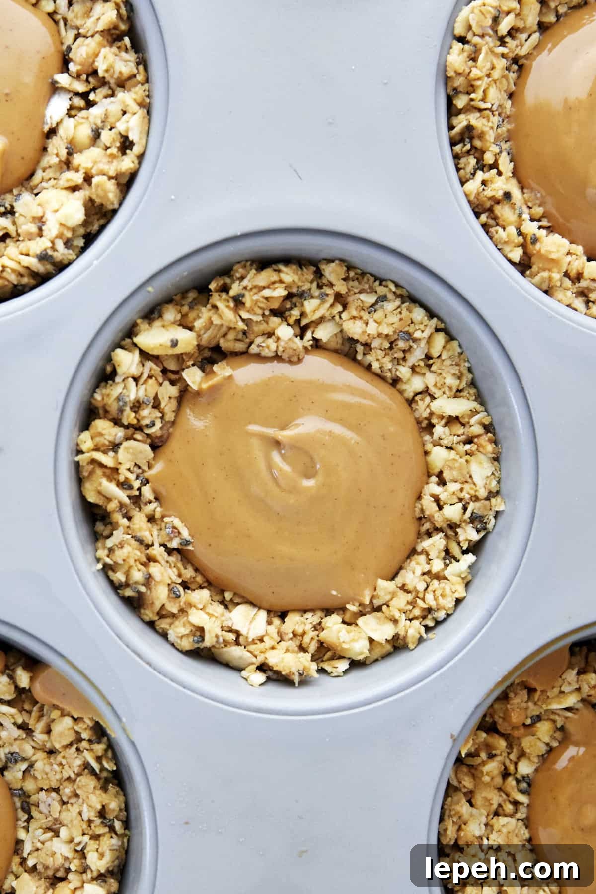 An oat cup in a muffin tin full of peanut butter. 