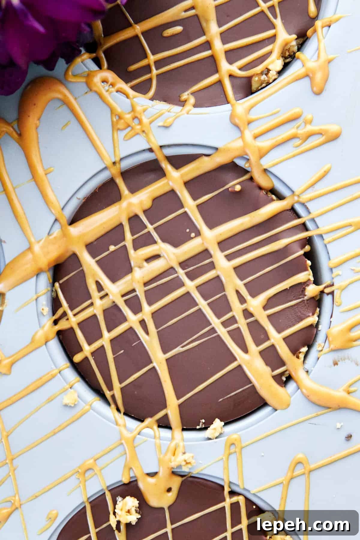 Peanut butter drizzled over a no bake peanut butter oat cup in a muffin pan.  