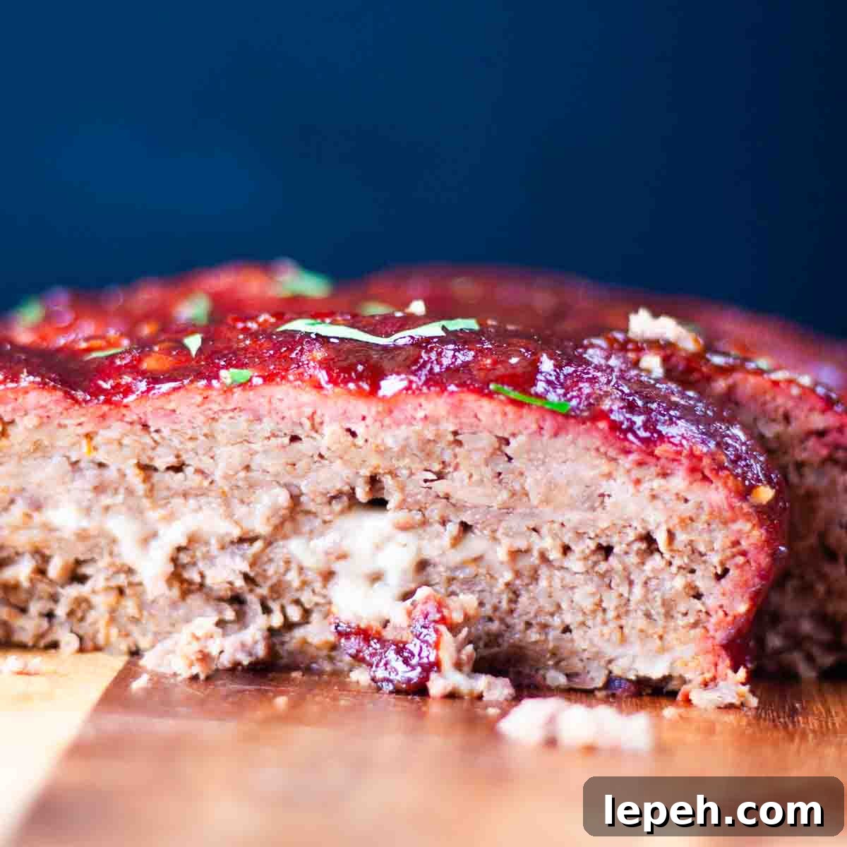 The meatloaf on a cutting board, with melty cheese oozing from the middle.