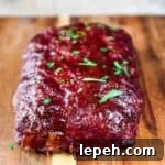 The barbecue glazed stuffed meatloaf on a wooden cutting board, garnished with fresh parsley.
