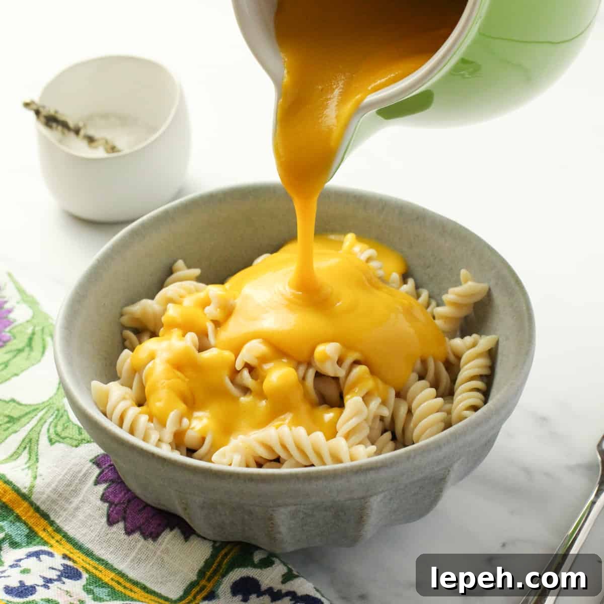 a pale blue bowl of pasta with vegan cheese sauce