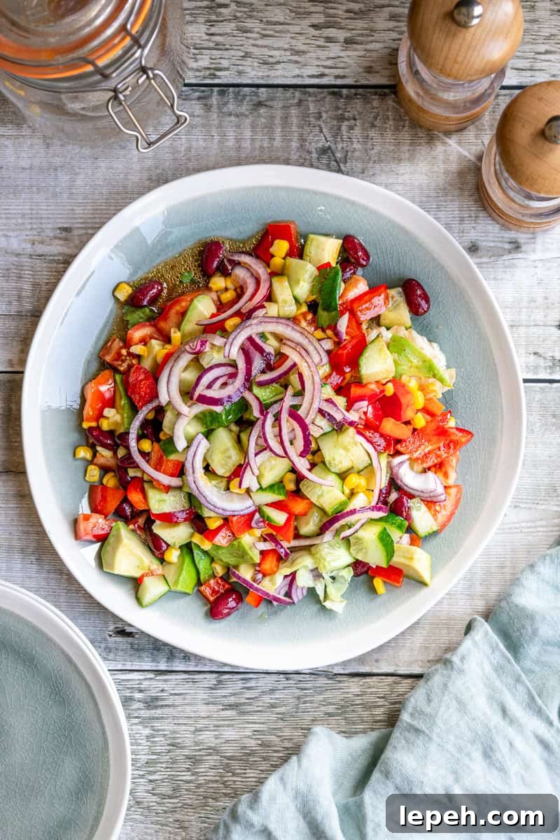 Plate of Mexican kilner jar salad with onions, avocado, kidney beans, tomatoes, bell peppers