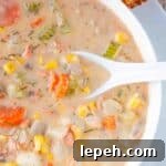 Instant pot smoked salmon chowder in a white bowl with a white spoon lifting up a spoonful of creamy chowder.