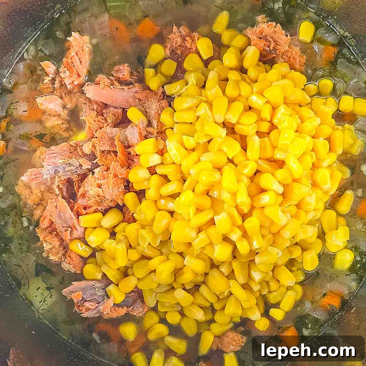 The salmon chunks and corn added to the pot.