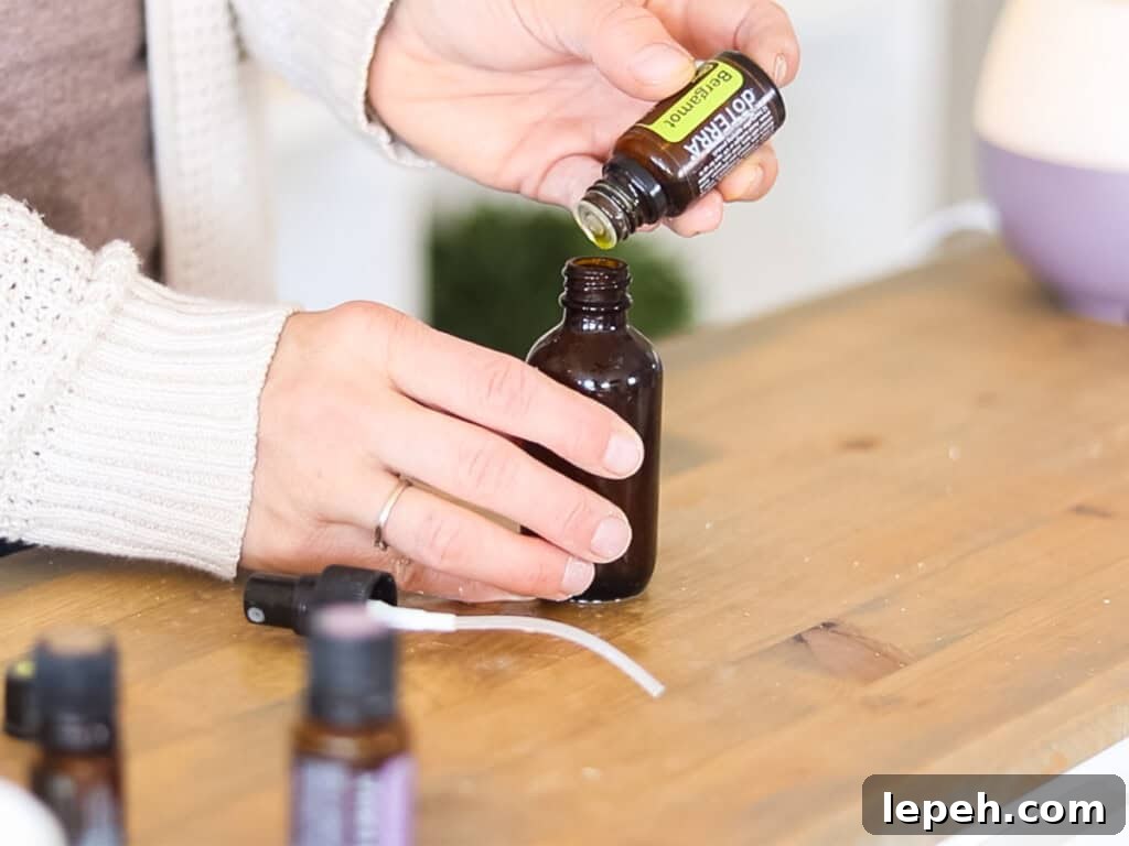 Dropping essential oils into an amber glass bottle.
