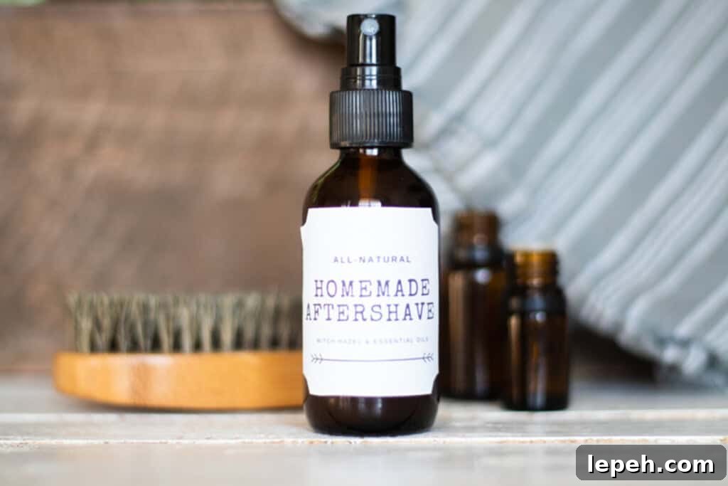 A bottle of homemade aftershave with a beard brush and essential oil bottles.