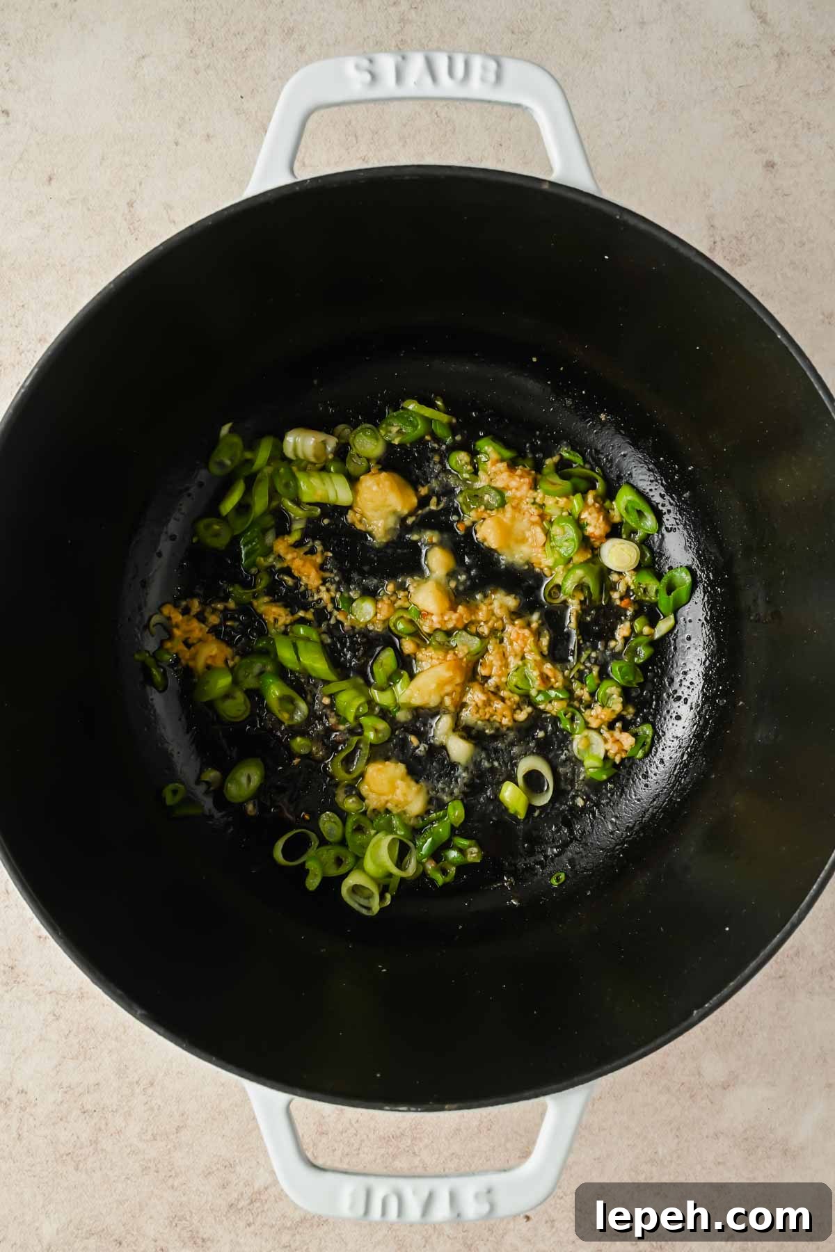 garlic and green onion sizzling in large pot.