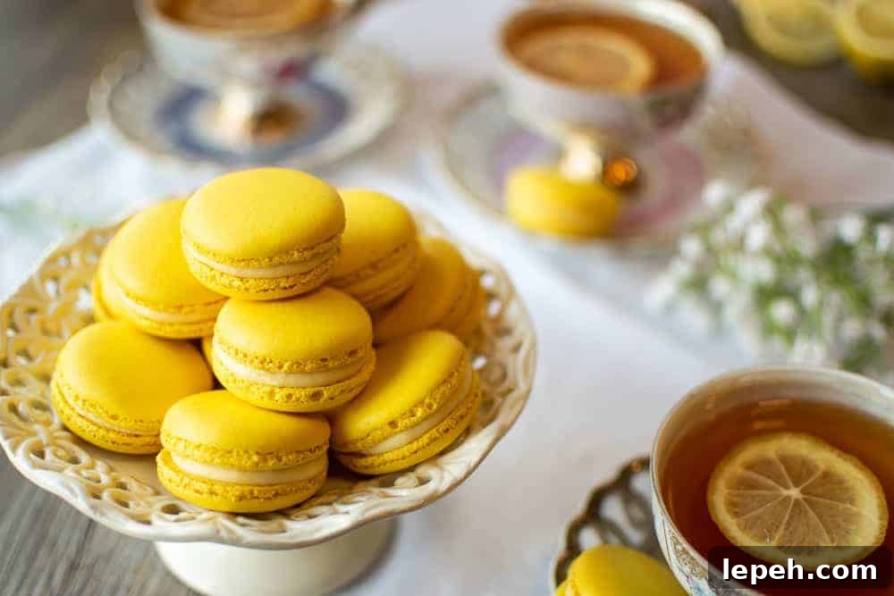 Lemon Macarons on white stand with three cups of lemon tea on a white cloth