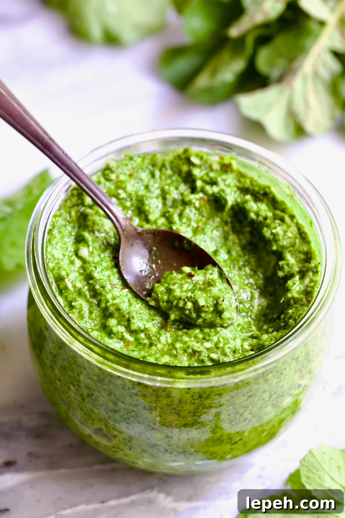 Radish Greens Pesto in glass jar with spoon scooping some up.
