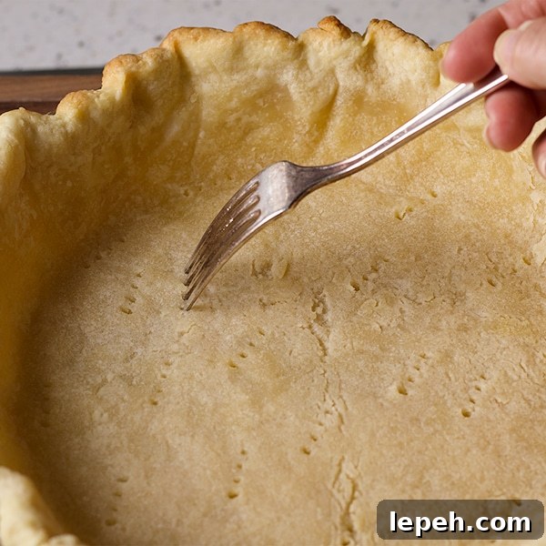 Poking holes in the bottom of a pie crust before baking.
