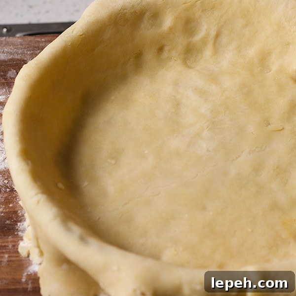 Pie crust dough fitted into a pie plate before the edges are trimmed.