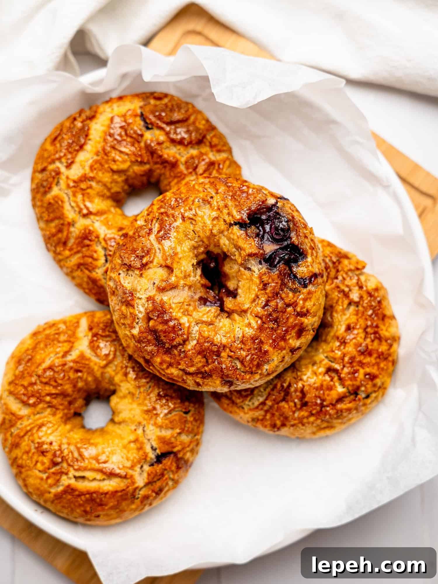 Four blueberry bagels on a plate.