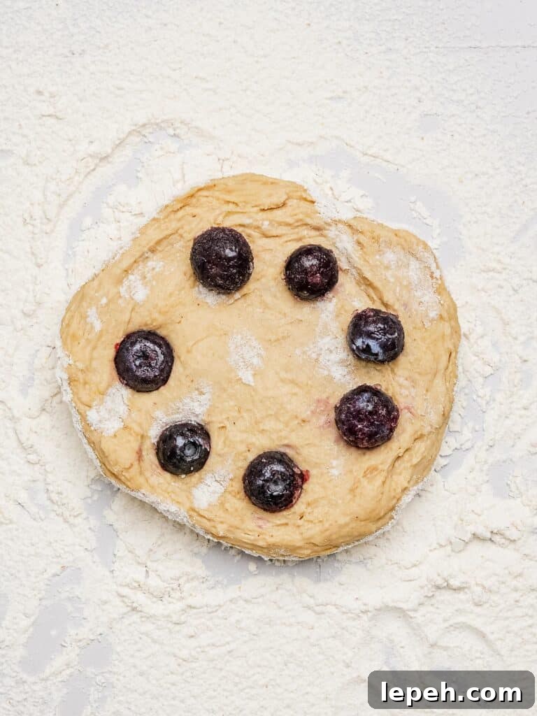 Adding blueberries to bagel dough to make blueberry bagels.