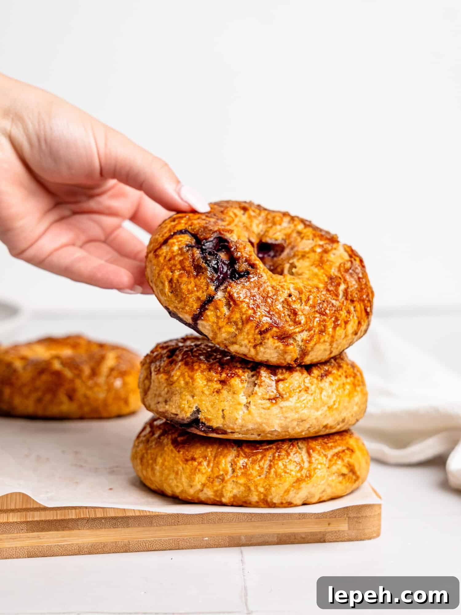 Three blueberry bagels stacked on top of each other.
