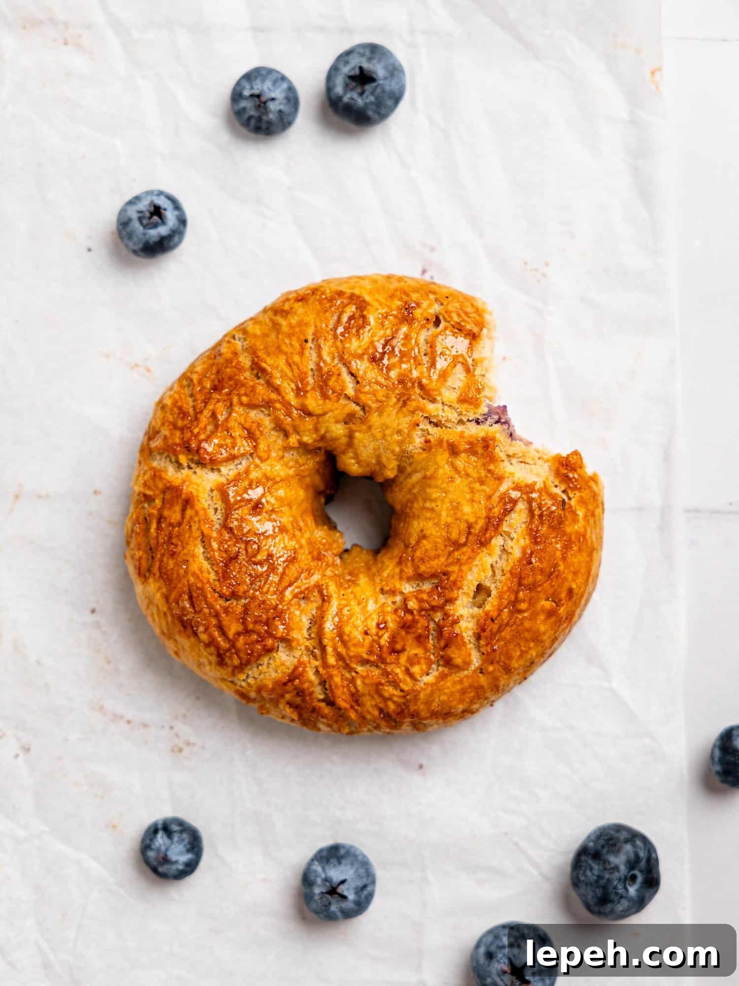 A blueberry bagel with a bite taken out.
