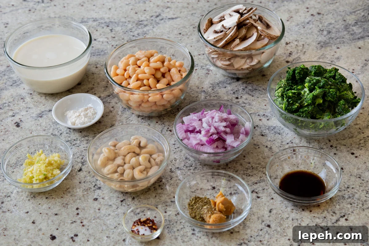 white beans, mushrooms, cashews, and other alfredo ingredients in bowls on a kitchen counter
