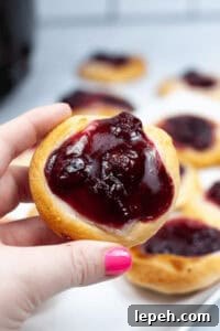 A hand holding an air fryer cherry danish.
