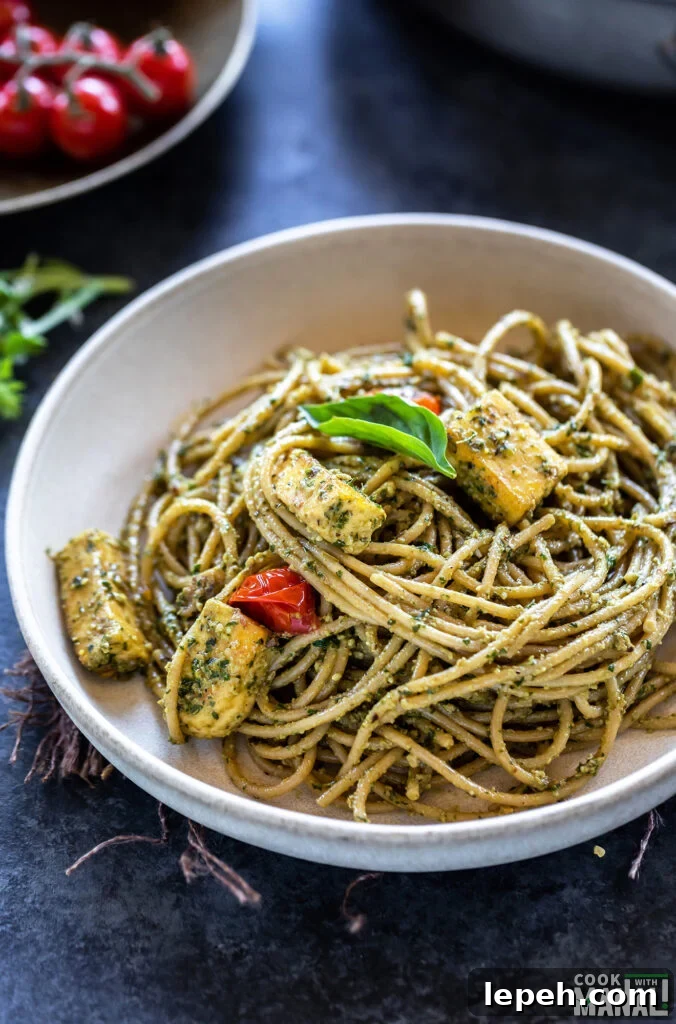 bowl of spaghetti tossed with pesto and paneer, garnished with basil