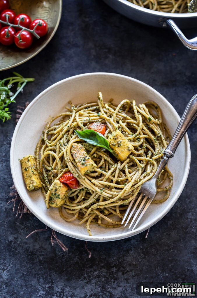bowl of spaghetti tossed with pesto with a fork placed on the side of the bowl