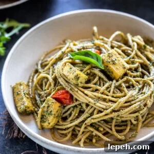 bowl of spaghetti tossed with pesto and paneer, garnished with basil