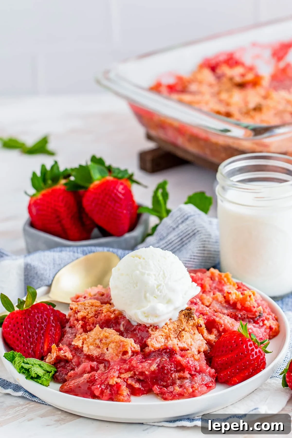 a serving of Strawberry Dump Cake on a plate with baking dish in the back