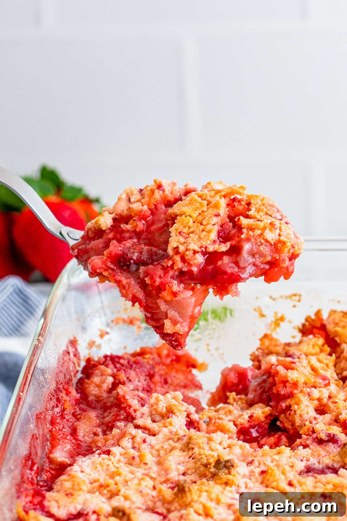 a spoon holding up a portion of Strawberry Dump Cake in air