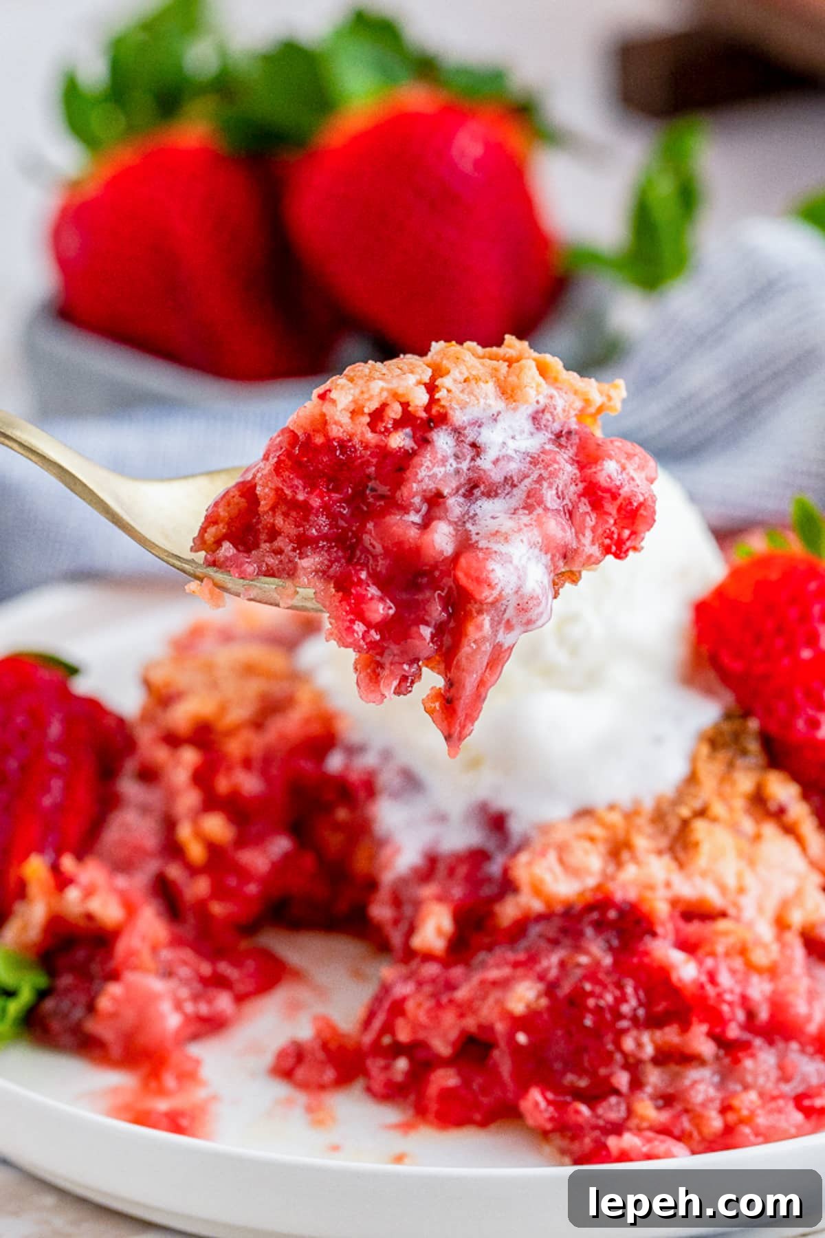 a spoon holding up a bite of Strawberry Dump Cake in air