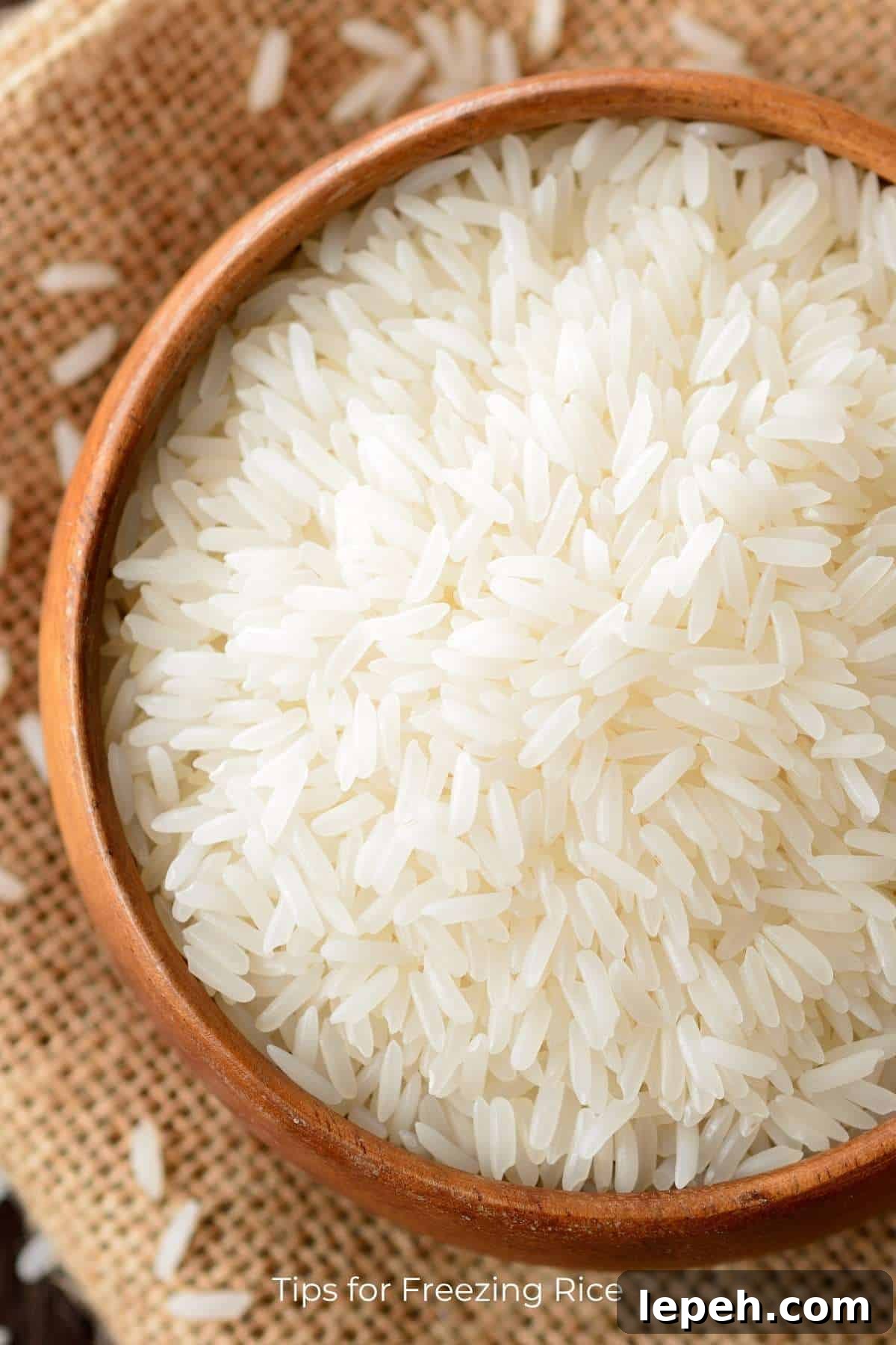 Top down view of a bowl of uncooked rice resting on a piece of burlap.