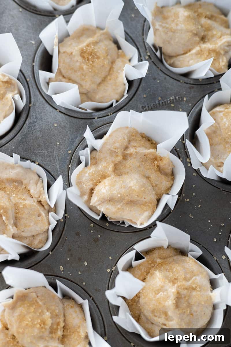 Batter in muffin cups sprinkled with turbinado sugar.