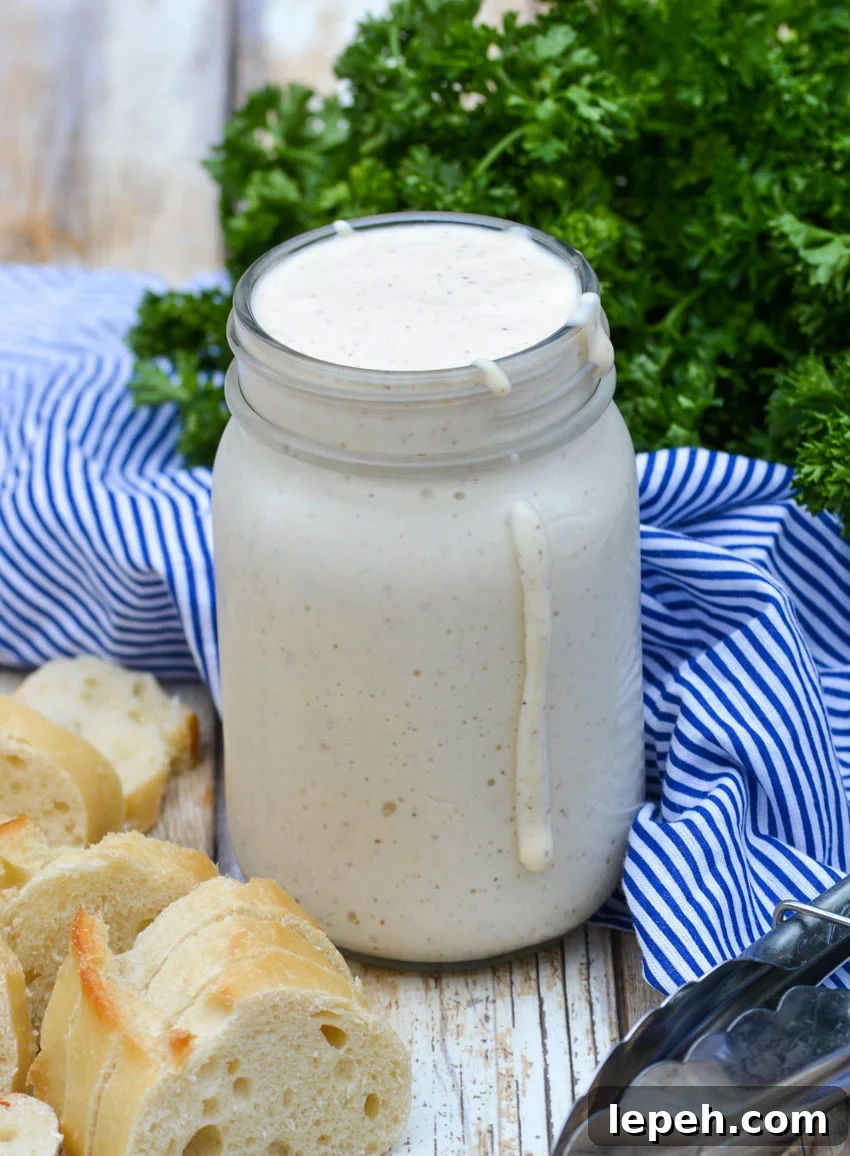 alabama white barbecue sauce in a glass mason jar with some dripping down the side