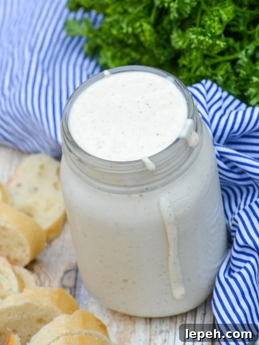 alabama white barbecue sauce in a glass mason jar with some dripping down the side