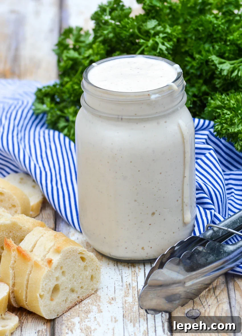 alabama white barbecue sauce in a glass mason jar with some dripping down the side