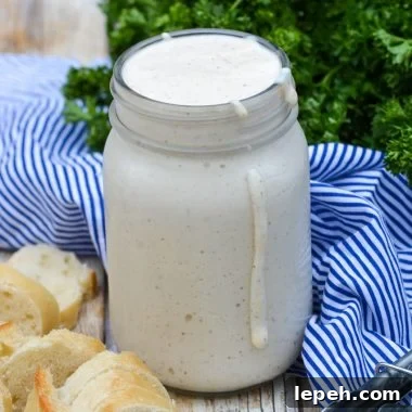 alabama white barbecue sauce in a glass mason jar with some dripping down the side