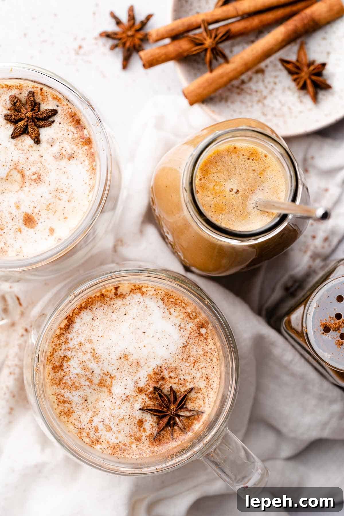pumpkin spice syrup in glass jar with two lattes and spices on the side