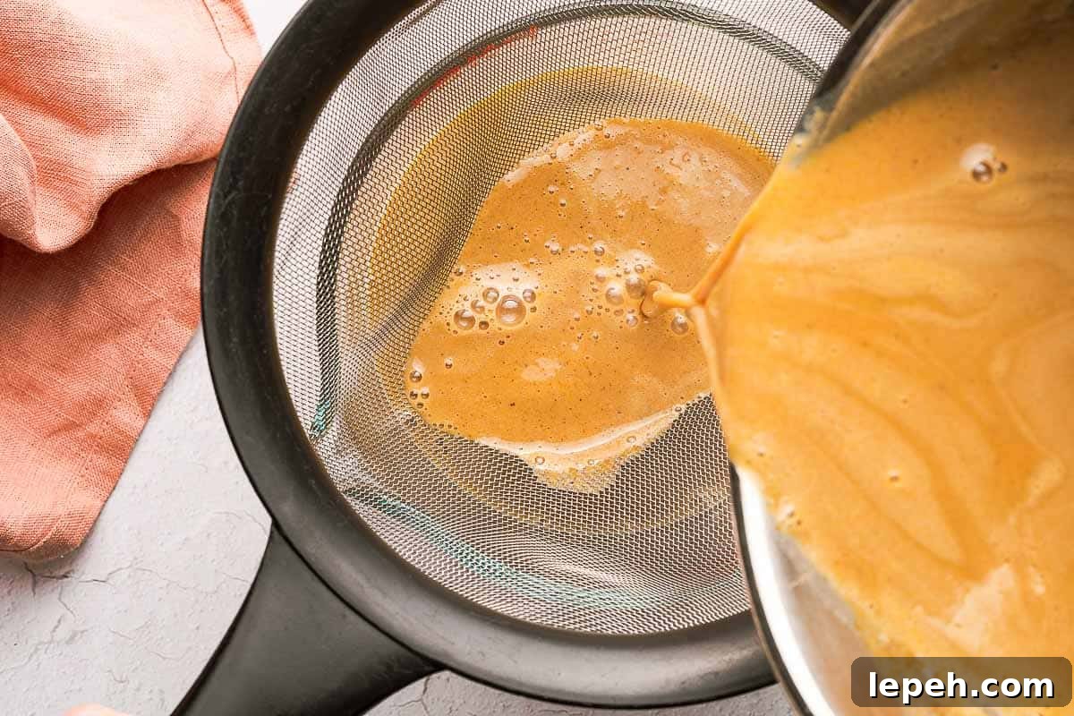 pumpkin spice syrup being poured through fine mesh sieve