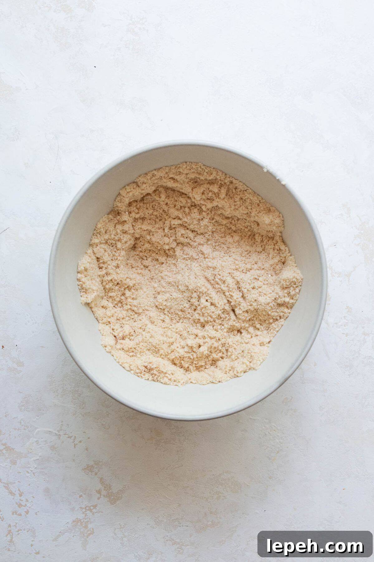 Dry ingredients for banana protein muffins whisked together in a bowl, including almond flour and vanilla protein powder.
