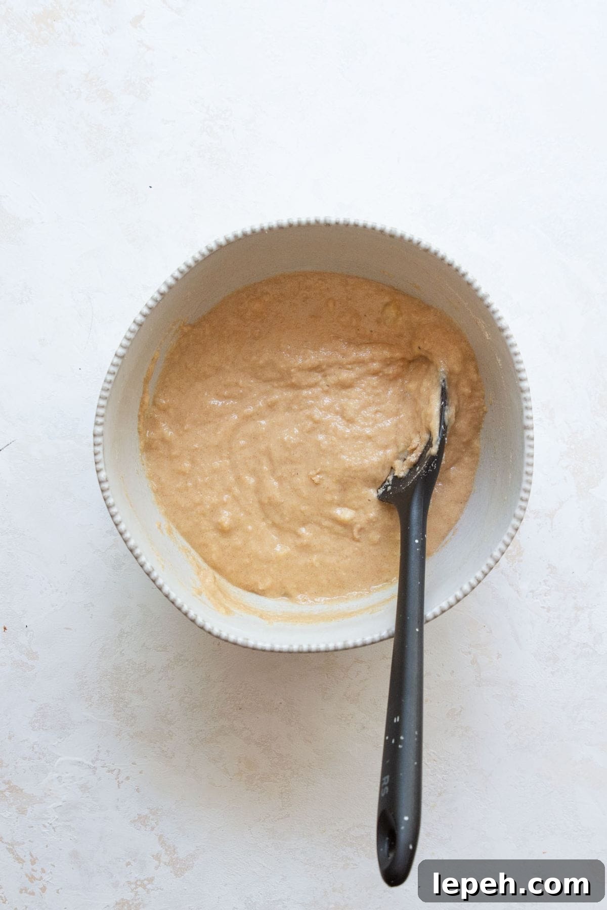 Banana protein muffin batter combined in a bowl, smooth and ready to fold in chocolate chips.
