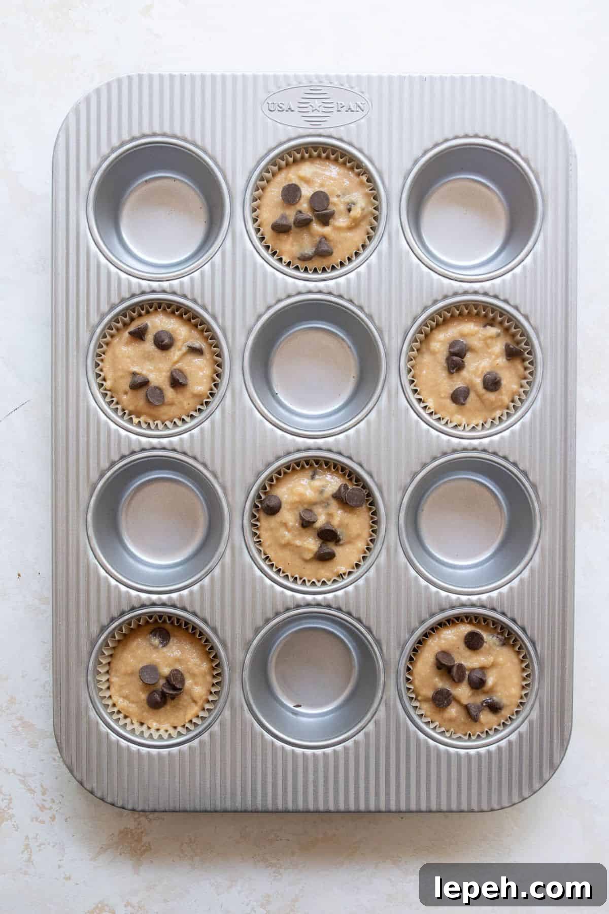 Banana protein muffin batter scooped into a muffin tin and ready to bake.