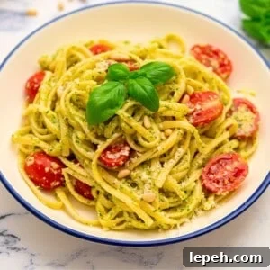 Bowl of pesto pasta tossed with fresh tomatoes and basil.