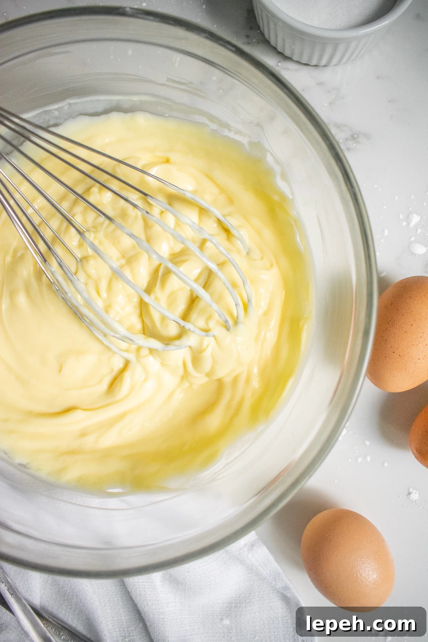 Pastry cream in a bowl with a whisk.