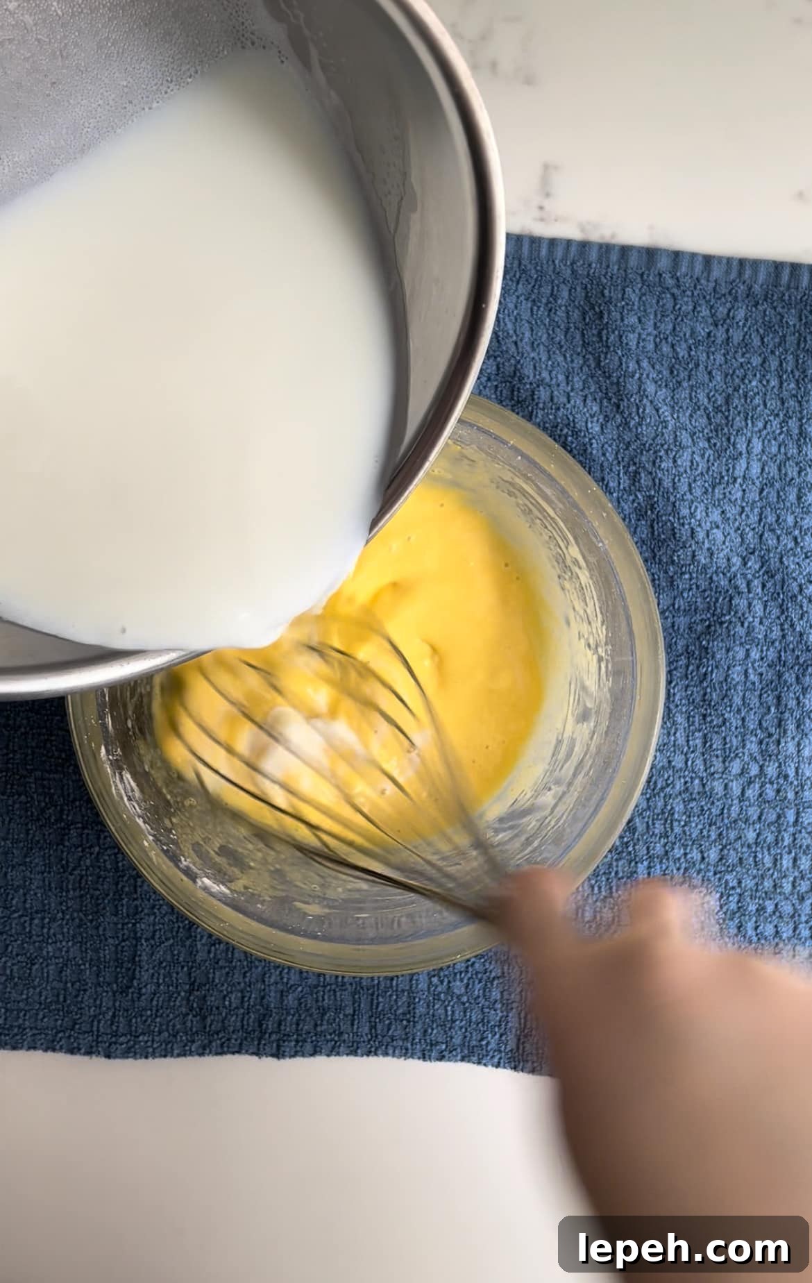 The process of tempering eggs when making pastry cream.