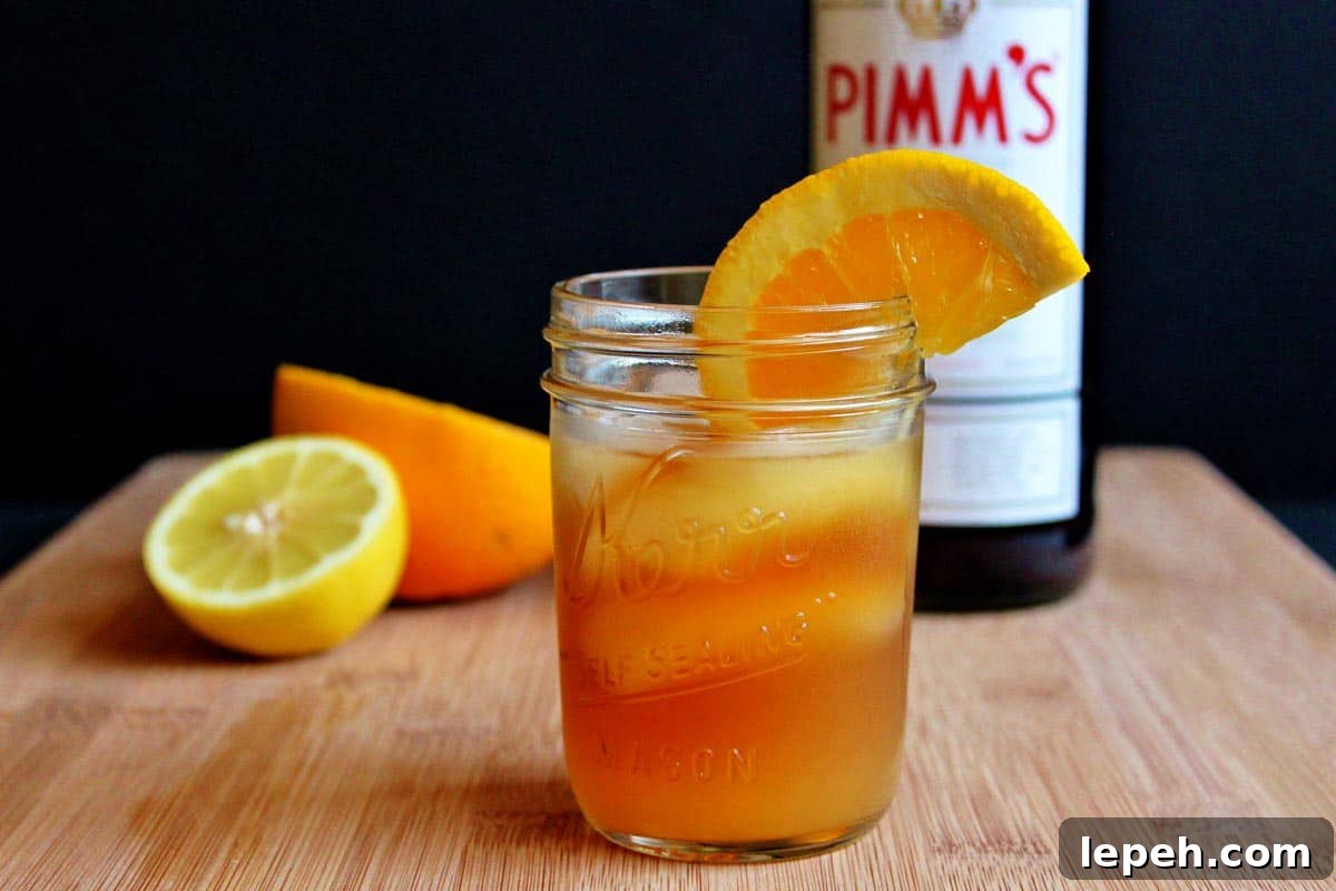 A glass of Pimm's sundowner cocktail in front of a bottle of Pimm's.