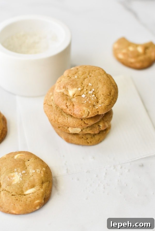 A stack of white chocolate chip cookies with sea salt on top