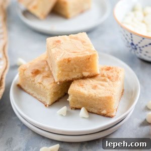 White chocolate brownies on a plate next to white morsels.