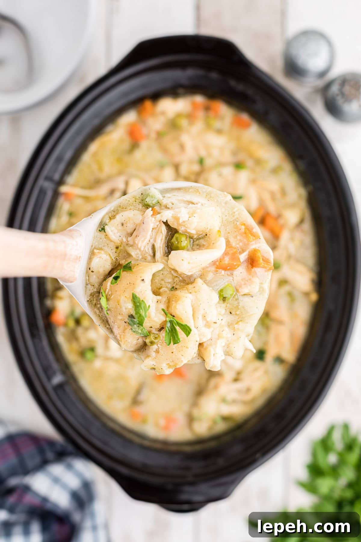 A ladleful of chicken and dumplings being removed from a slow cooker.